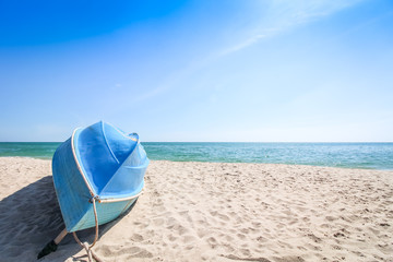 Small blue sailing boat upside down lays on the beach