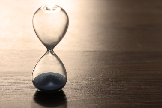 Close up hourglass on wooden floor for time concept, sepia effect used