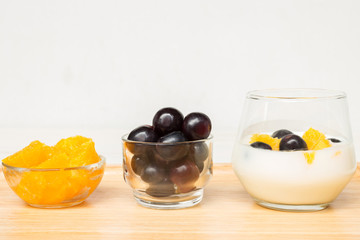 Fresh fruits with yogurt in a glass bowl on wood tray