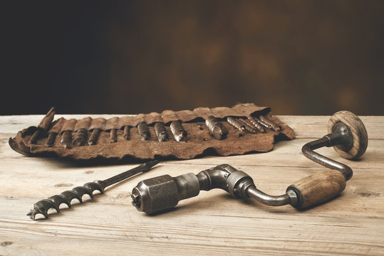 Drill brace with bits in leather tool roll on a wooden workbench