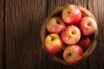 Red apples in a wooden bowl on dark background.