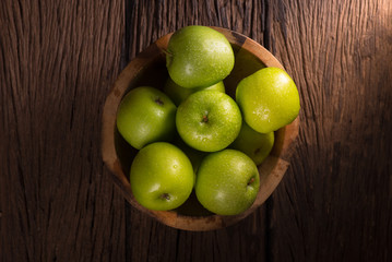 Fototapeta na wymiar Green apples in wooden bowl on wooden table.