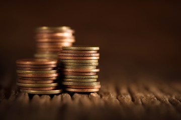 Coin stacks on wooden background.