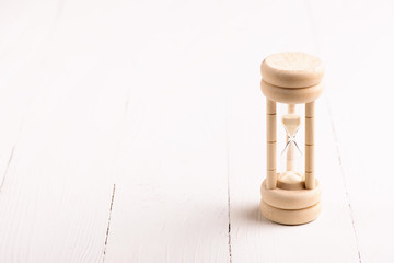 Hourglass on white wooden background.