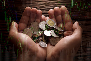 Double exposure of handful of coins and graph for finance and banking concept.