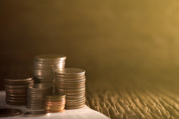 Row of coins and account book on the table with sunlight, banking and finance concept.