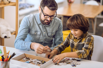 Father and son making picture of puzzles