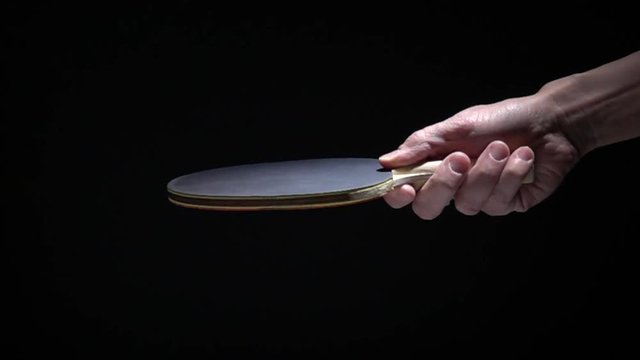Hand holding table tennis racket and bouncing ping pong ball. Slow motion film clip with sport equipment.