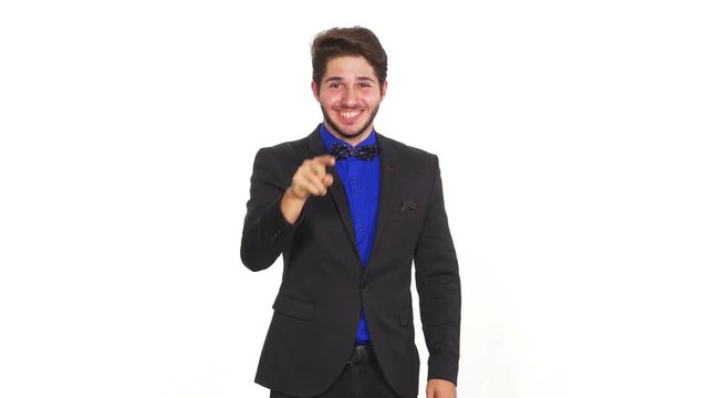 Happy young unconvinced man on a white background pointing with a finger