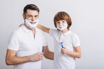 Positive delighted males holding razors