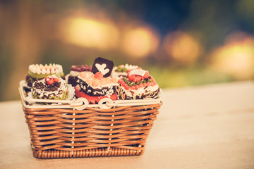 Fototapeta na wymiar Close up small cake in basket with bokeh nature background. Vintage or retro tone. Copy space.
