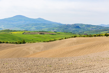 Fototapeta na wymiar Soil field in a rolling landscape with mountains in the background