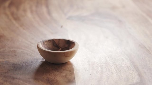 cumin seeds falling in wood bowl on wooden table in slow motion, 180fps prores footage