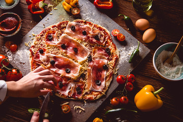 Girl is preparing homemade pizza on wooden table
