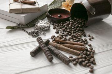 Set of coffee beans and chocolate sweets and packs and pocket watch. White wooden background. Space for text