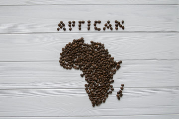 Map of the Africa made of roasted coffee beans laying on white wooden textured background and space for text