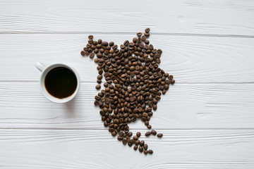 Map of theNorthern America made of roasted coffee beans laying on white wooden textured background with cup of coffee and space for text