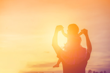 Father took the baby learn to walk at sunset.