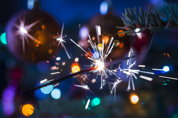 sparkler on christmas tree on colorful blurry background