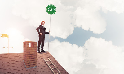 Businessman in suit on house top with ecology concept signboard.