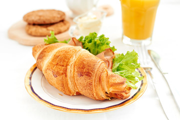 Healthy breakfast croissant sandwich with ham fresh salad orange juice with mint on white background