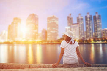 Obraz premium Woman sitting in the city park near the river looks at the town