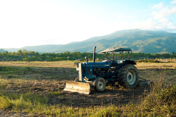 Obraz premium soil tractor in the farmland with beautiful mountain behind