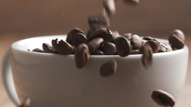 roasted coffee beans falling in slow motion into cappuccino cup and poured out on table, 180fps prores footage
