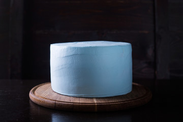 Blue souffle cake with chocolate icing on a dark wooden background