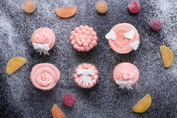 Pink cupcakes on a dark background with flour, top view, pink cream