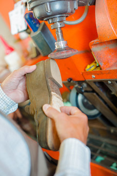 Cobbler shaping heel of shoe on a machine
