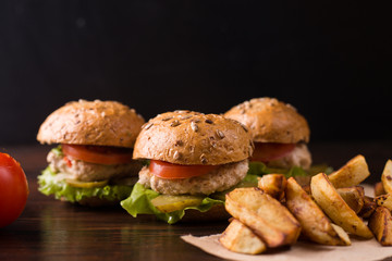 Three burgers on a dark wooden table