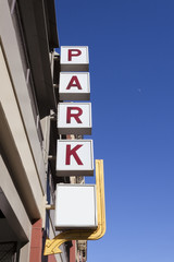 Urban parking deck with red on white PARK sign. Blue sky. Vertical.