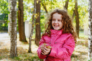 Laughing little girl throws the leaves.