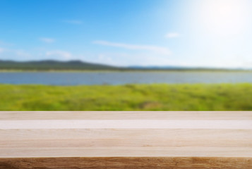 Empty wooden table and landscape background of forest lake and sky with sunshine. 