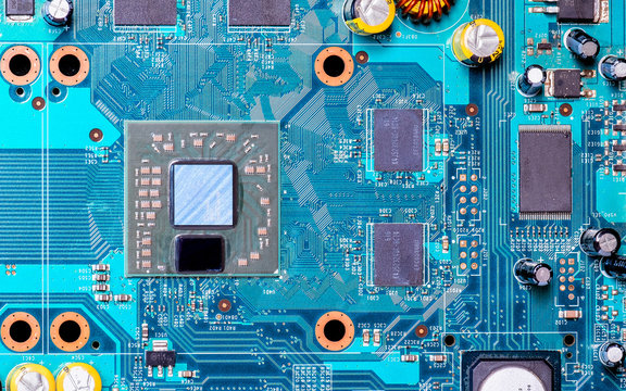 Photo of processor or central processing unit (CPU) in electronic device,  there  also show few microchip and yellow capacitor on blue printed circuit board (PCB)