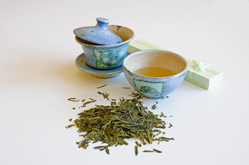 Blue cup of tea with pot, spill tea leaves and green box - gift on a white background