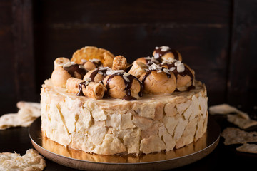 Napoleon cake on a dark wooden background decorated with petals of almonds eclairs, waffles and chocolate icing