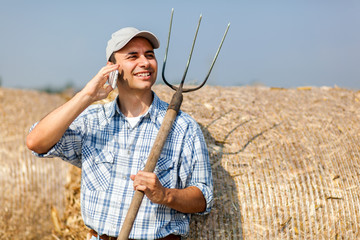 Young farmer in a meadow talking at the phone