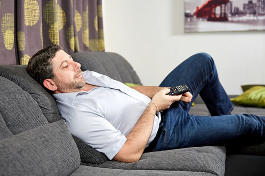 Caucasian man sitting on couch at home watching tv