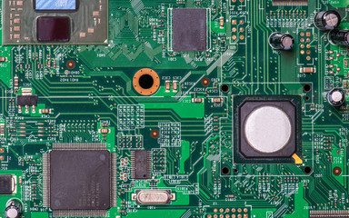 Photo of processor or central processing unit (CPU) , microchip, resistor and capacitor in, on green printed circuit board (PCB), this is part of some electronic device