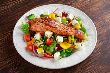 Fried Salmon steak with fresh vegetables salad, feta cheese. concept healthy food.