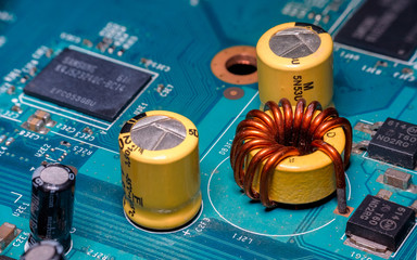 Photo of  electric component in electronic device, contain copper coil, yellow capacitor and black...