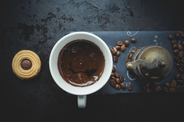 Top view of cup of coffee, coffee grains nd cookies on a dark base ...