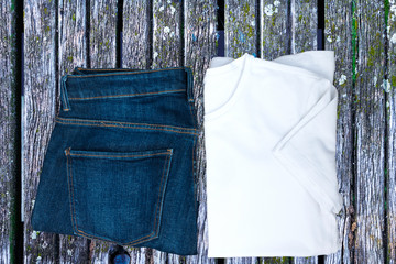 White T-shirt, denim jeans on a wooden board. Top view, Copy space.