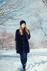 Beautiful woman in black fur coat posing. Outdoor winter portrait