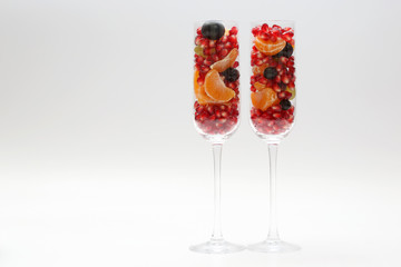 two glasses filled with fruit on a light background