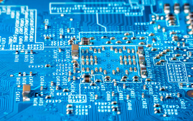 Photo of  electric component in electronic device, contain small resistor in beautiful rectangle formation, small capacitor, microchip and capacitor on blue printed circuit board.