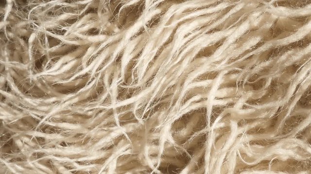 Modern shaggy woven shiny acrylic hairs slow tilt 4K 2160p 30fps UltraHD footage - Beige threads of faux fur blanket close-up 3840X2160 UHD tilting video