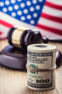 Judge's hammer gavel. Justice dollars banknotes and usa flag in the background. Court gavel and rolled banknotes. Still life of a bribery, corruption in the US judicial system.